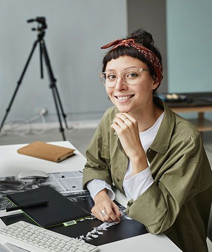 Mujer sonriente con gafas edita fotografías en una tableta gráfica